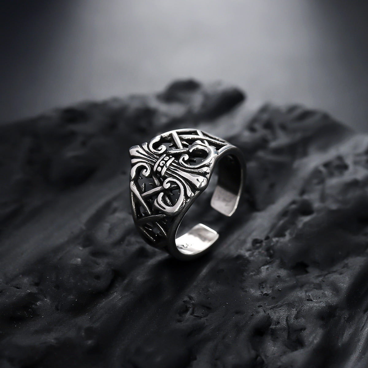 Silver ring with intricate design on a textured surface