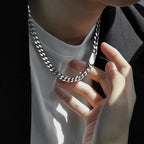 Person holding a silver chain necklace with a blurred background