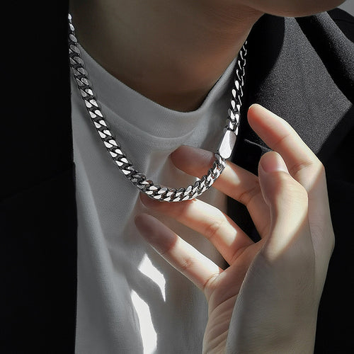 Person holding a silver chain necklace with a blurred background