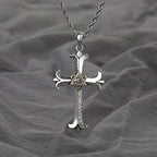 Silver cross pendant with eye design on a gray fabric background