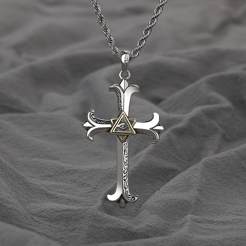 Silver cross pendant with eye design on a gray fabric background