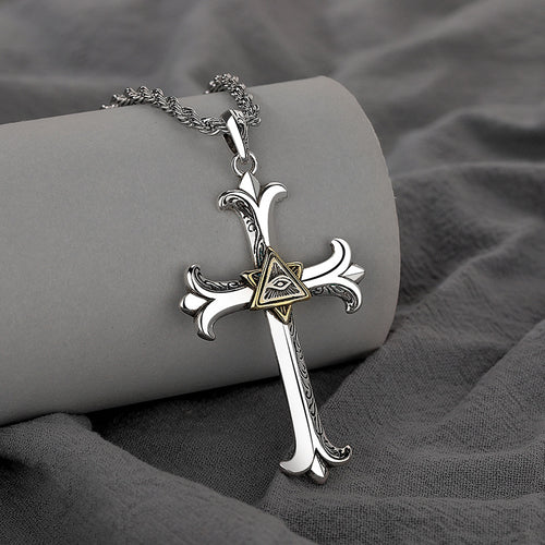 Silver cross necklace with a gold triangle pendant on a gray fabric background