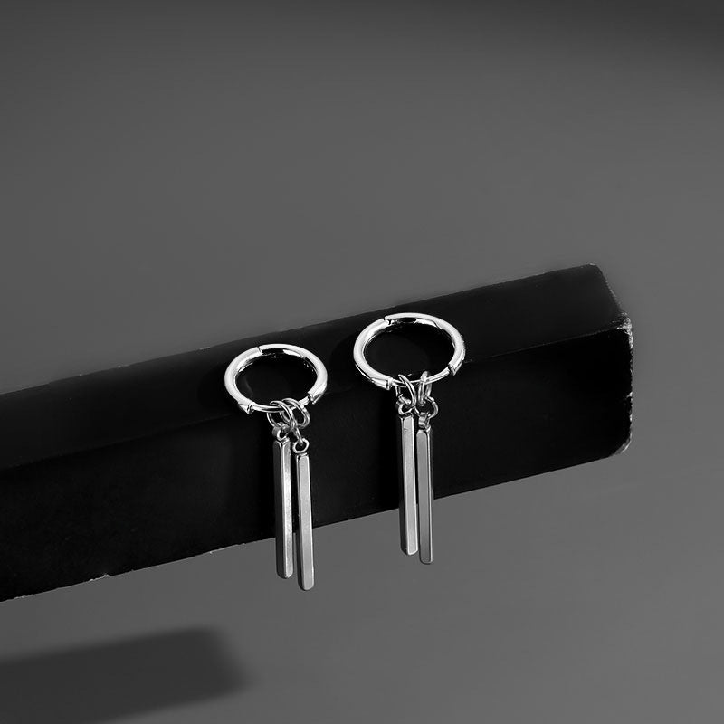 Pair of silver earrings with dangling bars on a black stand against a gray background