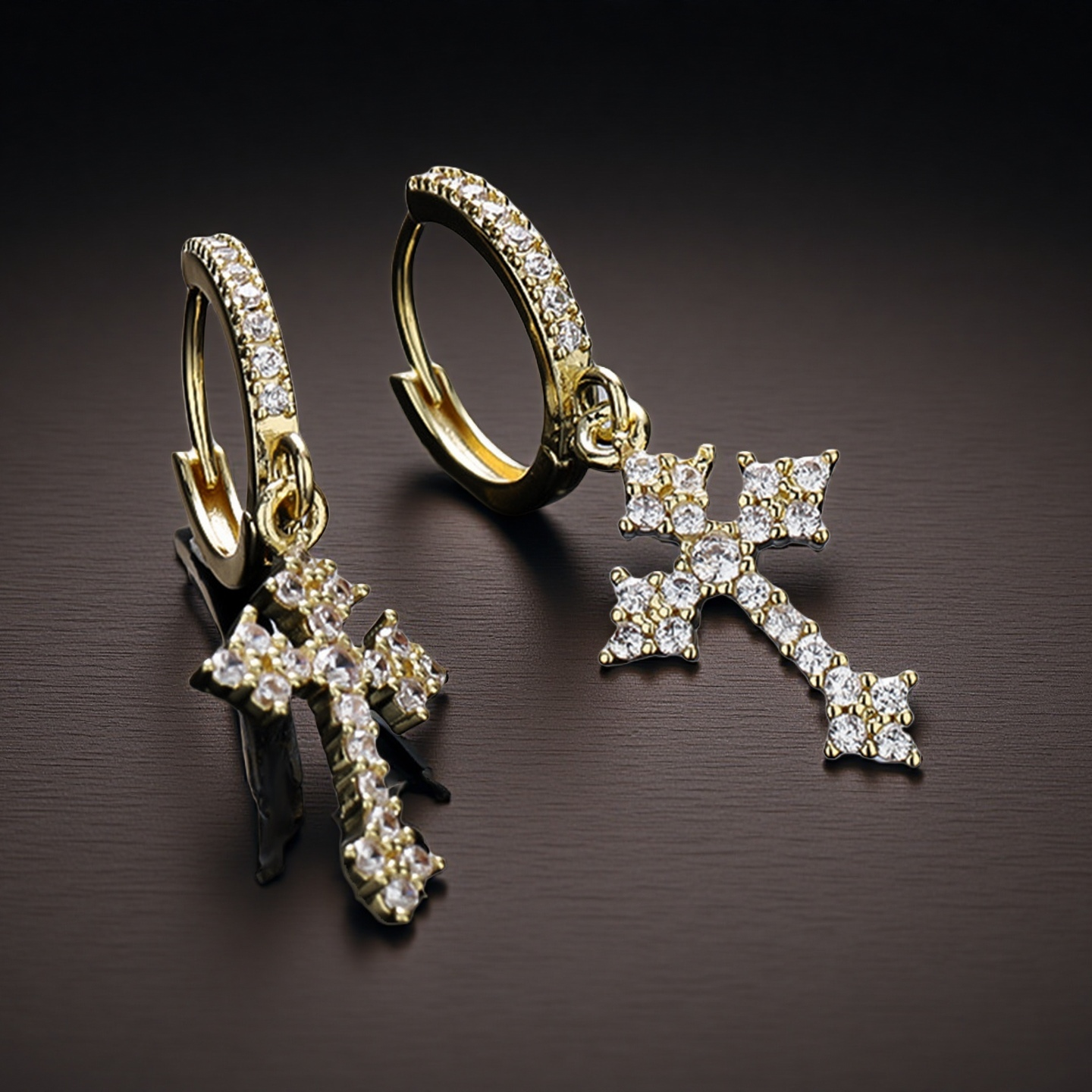 Gold hoop earrings with diamond-studded cross pendants on a dark surface