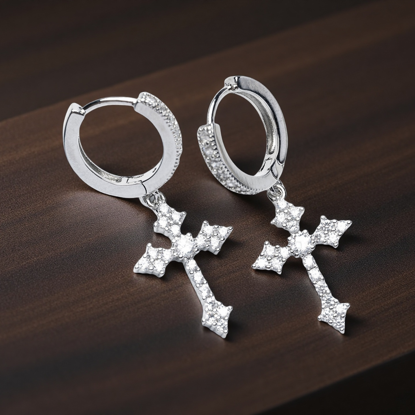 Silver hoop earrings with cross pendants on a wooden surface