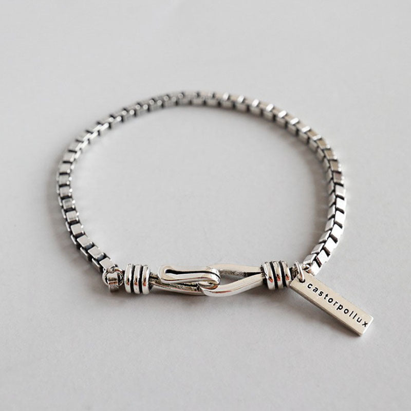 Silver bracelet with a tag on a light gray background