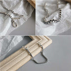 Silver necklace on a textured surface with close-up details.