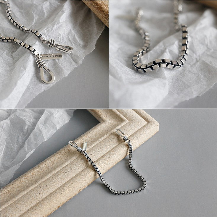 Silver necklace on a textured surface with close-up details.