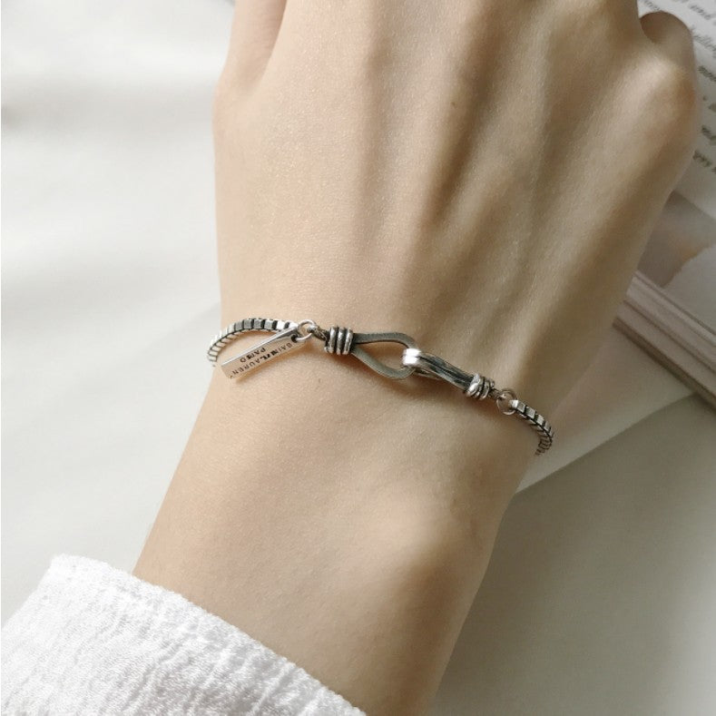 Silver bracelet on a wrist with a plain background