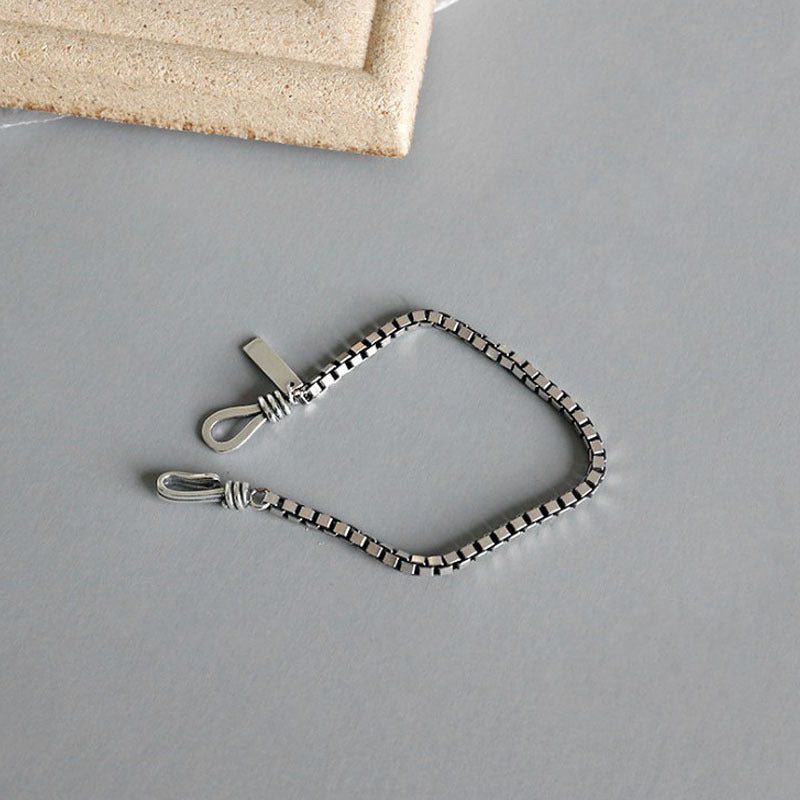Silver chain with clasp on a gray surface