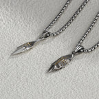 Two silver arrowhead pendants on chains against a light gray background