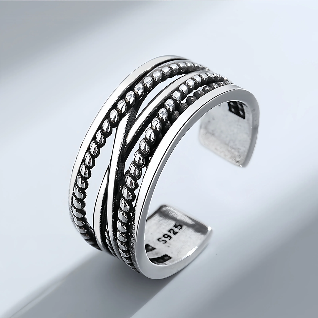 Silver ring with intricate design on a light gray background