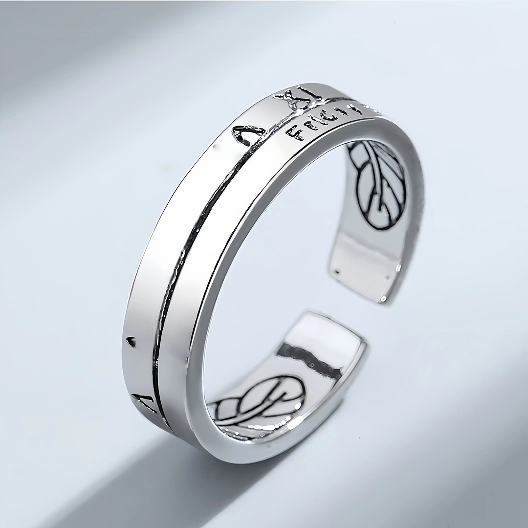 Silver open ring with engraved designs on a light gray background