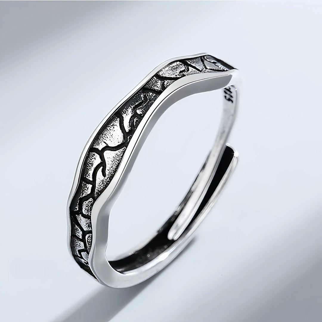 Silver ring with intricate design on a light gray background