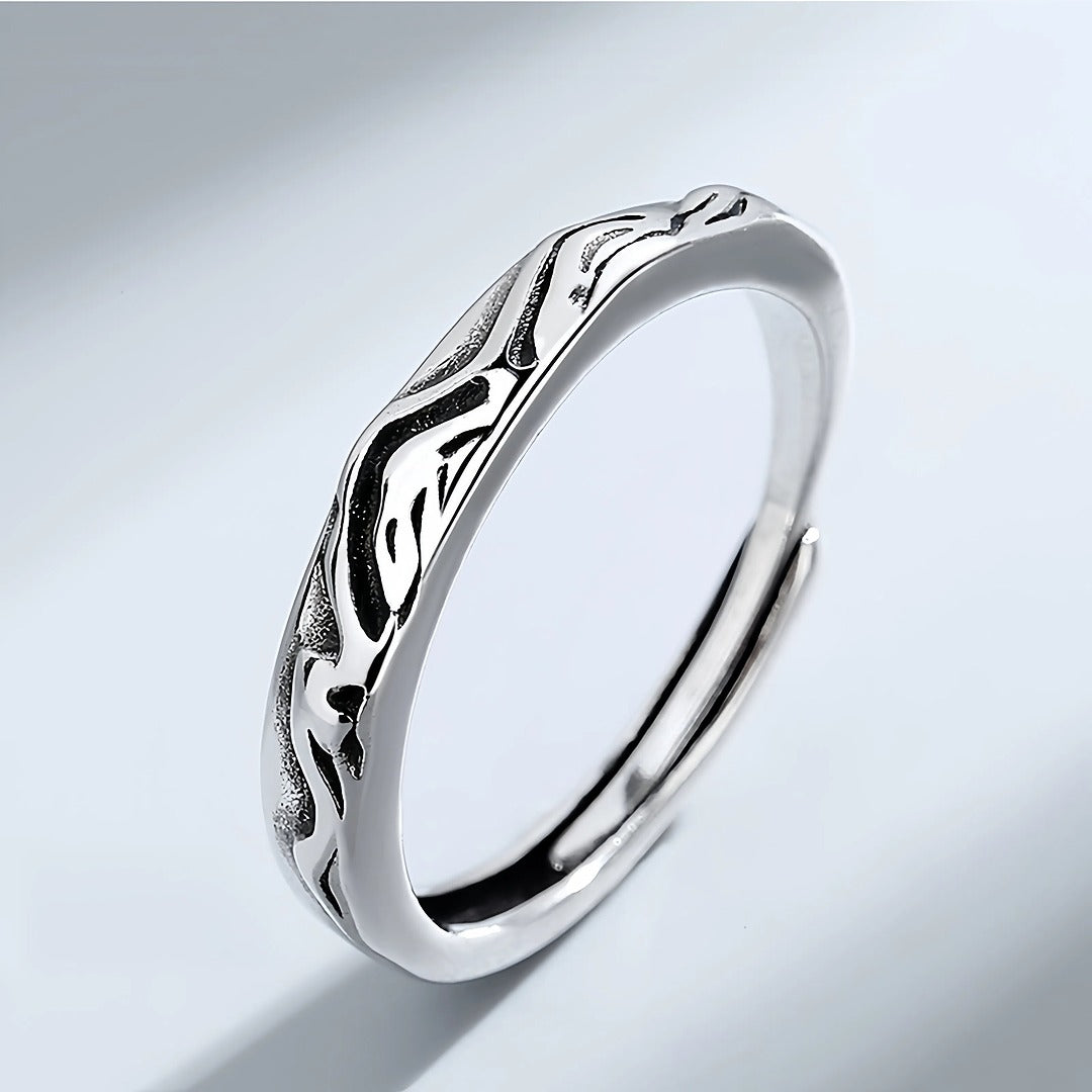 Silver ring with wavy design on a light gray background