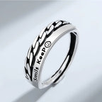 Silver ring with braided design and 'Smiles Keep' engraving on a light gray background