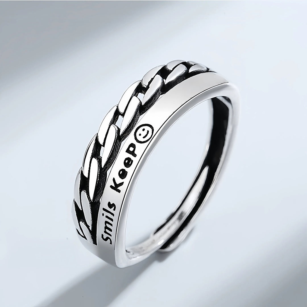 Silver ring with braided design and 'Smiles Keep' engraving on a light gray background