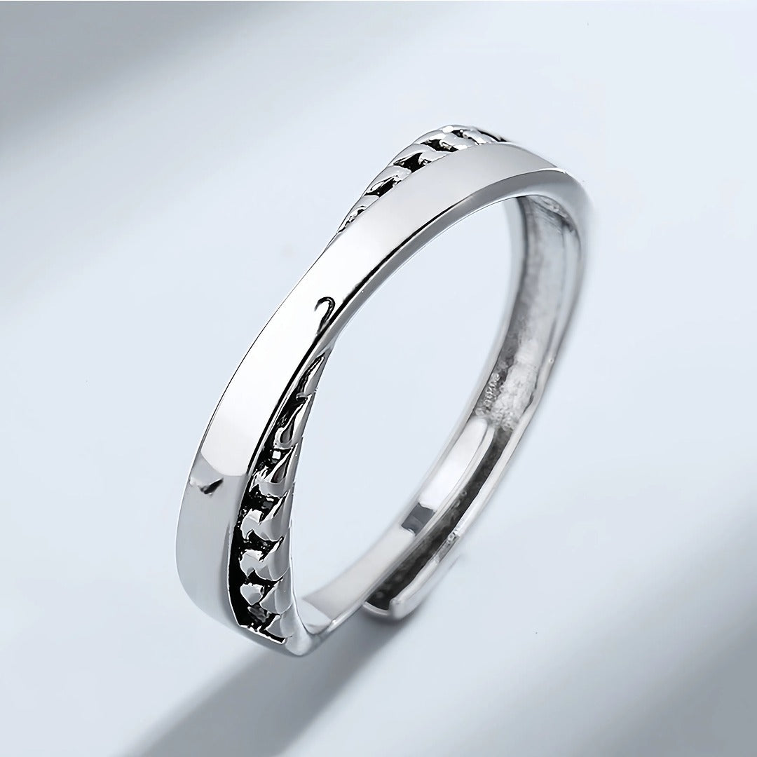 Silver ring with textured design on a light gray background
