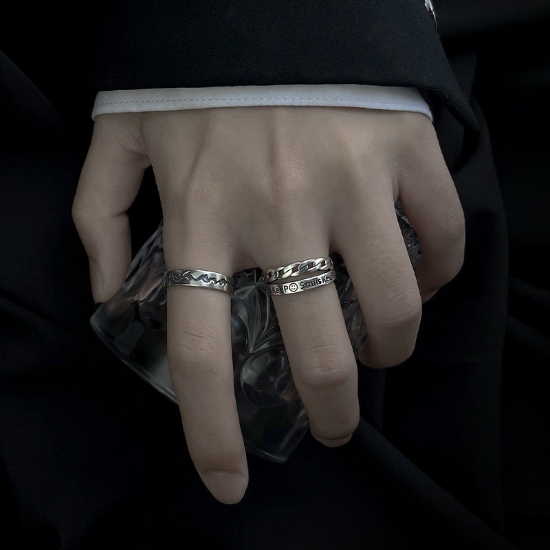 Close-up of a hand wearing two silver rings on a dark background