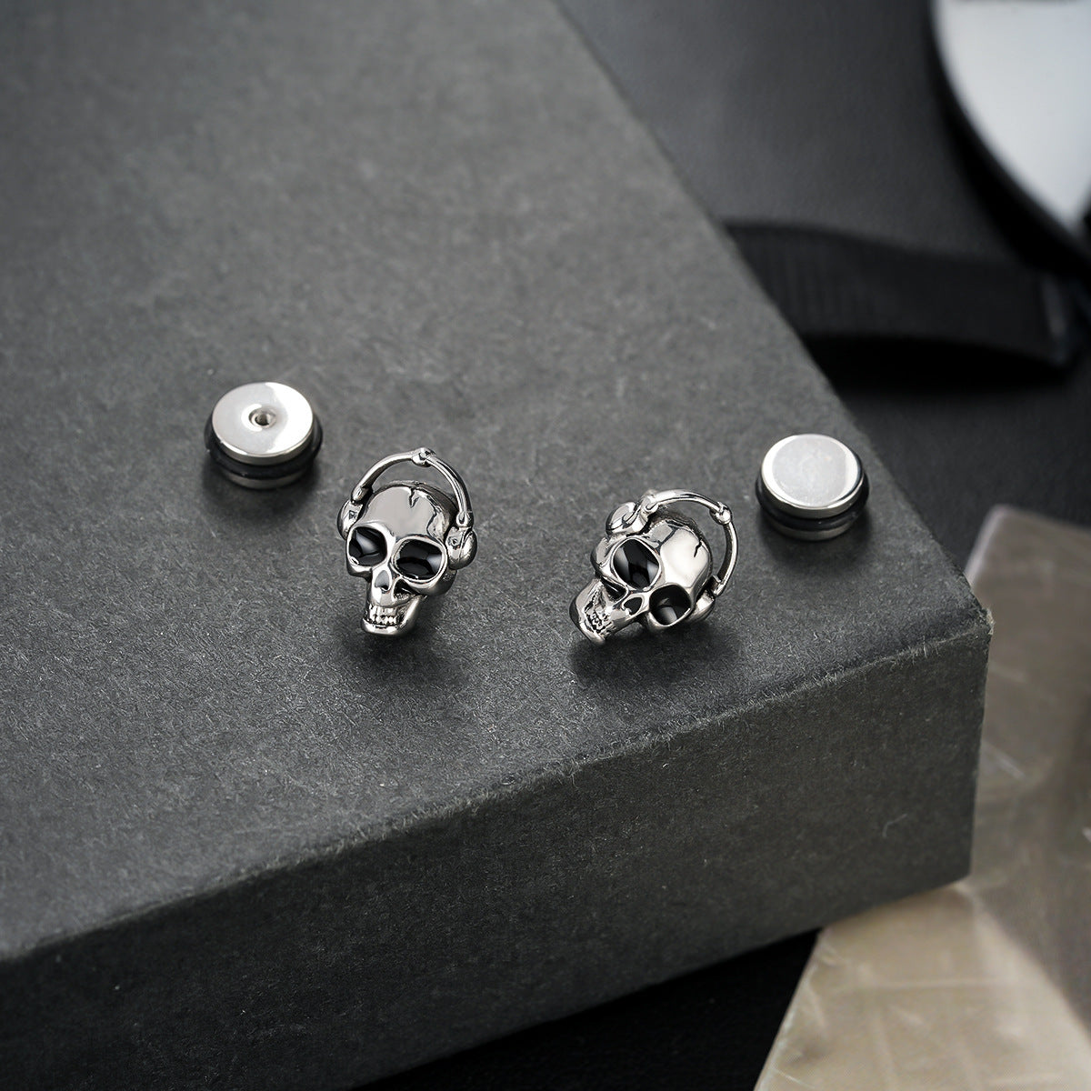 Skull-shaped earrings on a dark surface