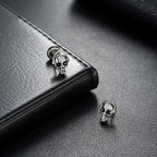 Skull-shaped earrings on a black leather surface