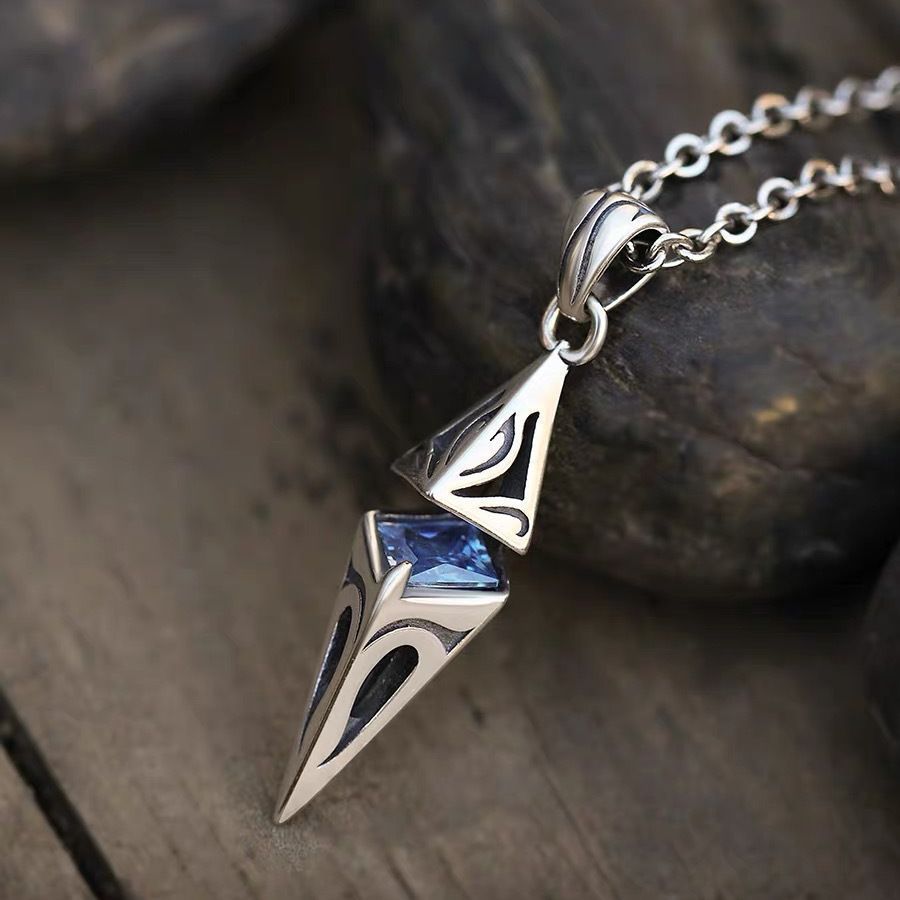 Silver pendant with blue gemstone on a wooden surface