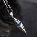 Silver pendant with blue gemstone on a dark background