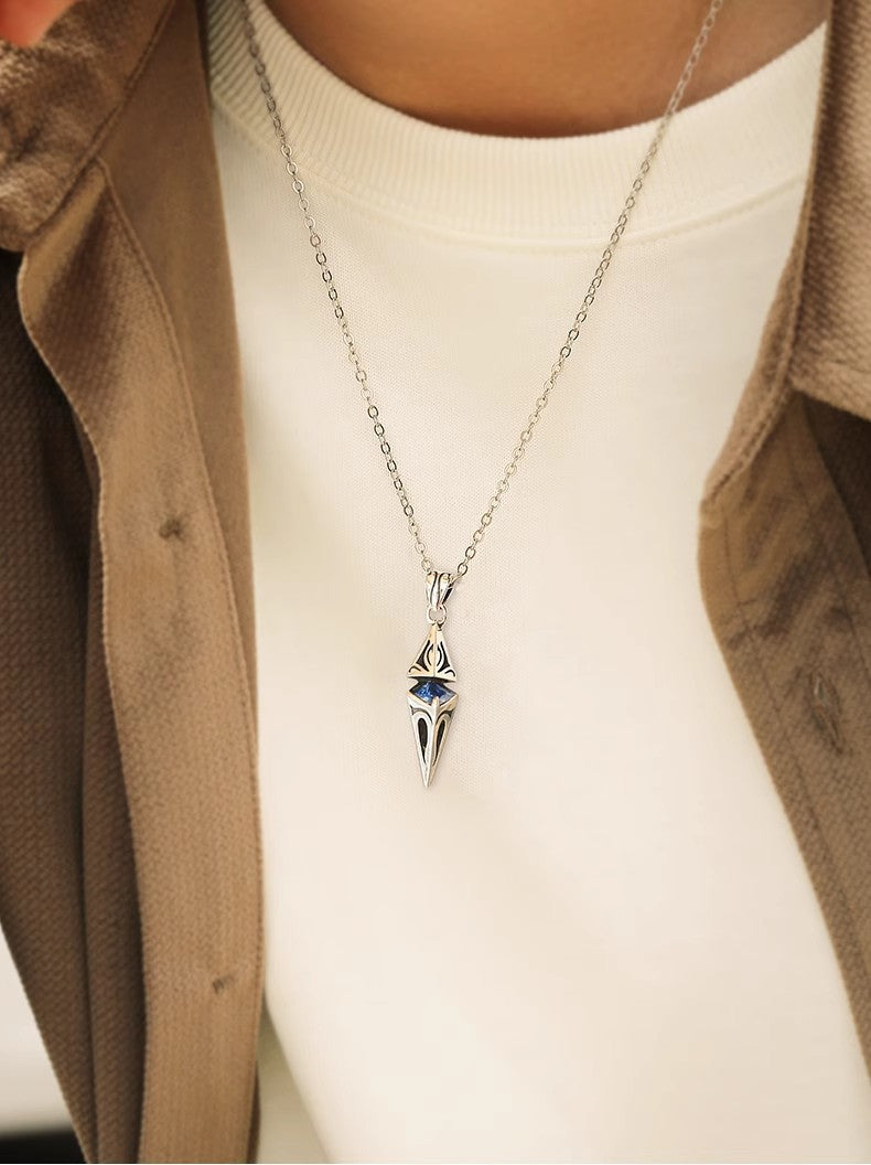 Silver necklace with a pendant worn by a person in a brown coat and white shirt.