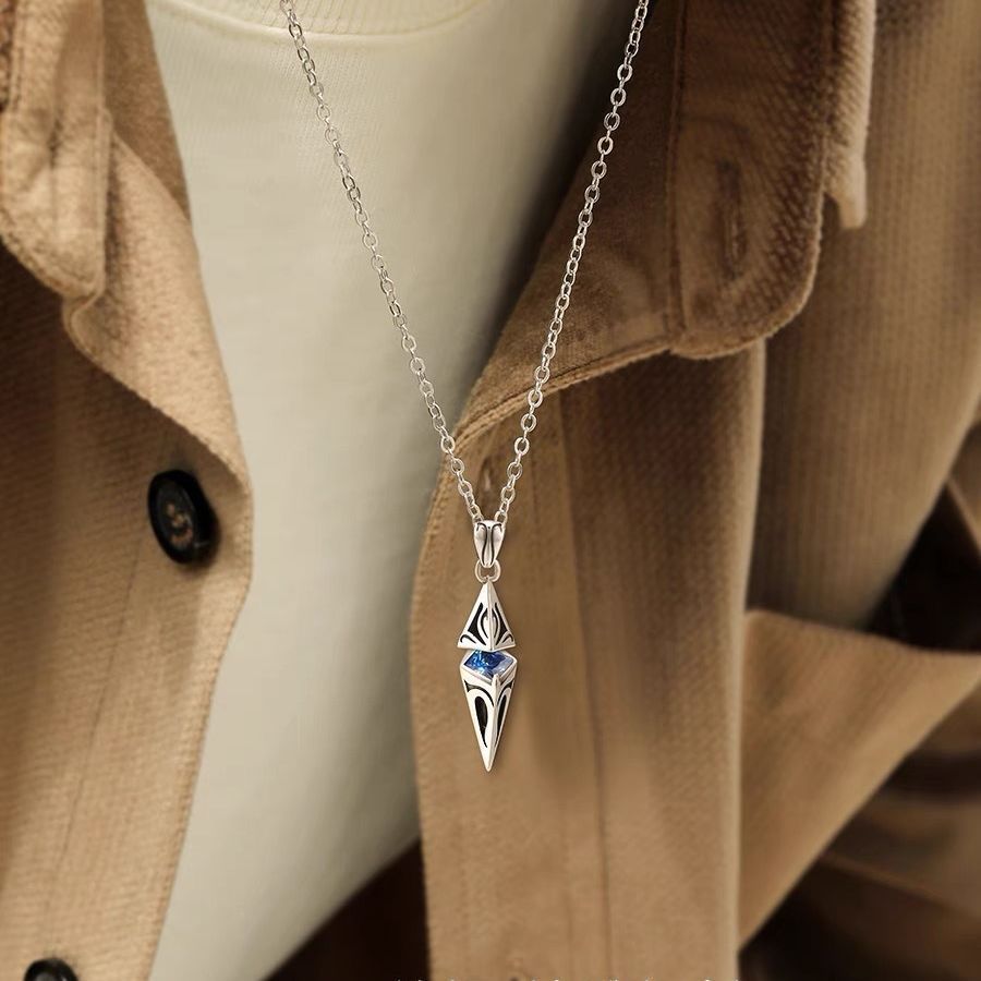 Silver necklace with a pendant on a mannequin wearing a beige coat.