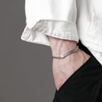 Silver bracelet on a wrist with a gray background