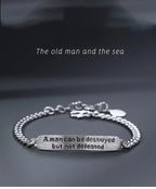 Silver bracelet with motivational quote on a dark background