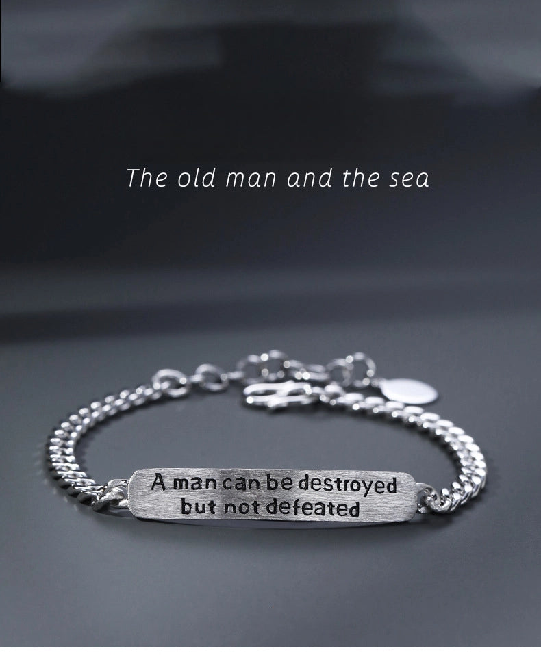 Silver bracelet with motivational quote on a dark background
