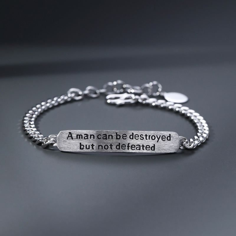 Silver bracelet with motivational quote on a dark background