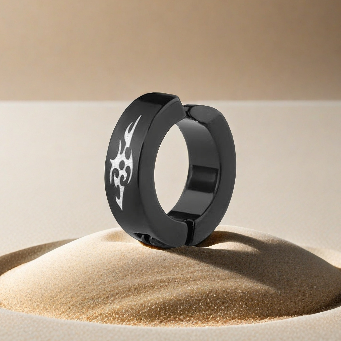 Black ring with a white symbol on a beige sand background