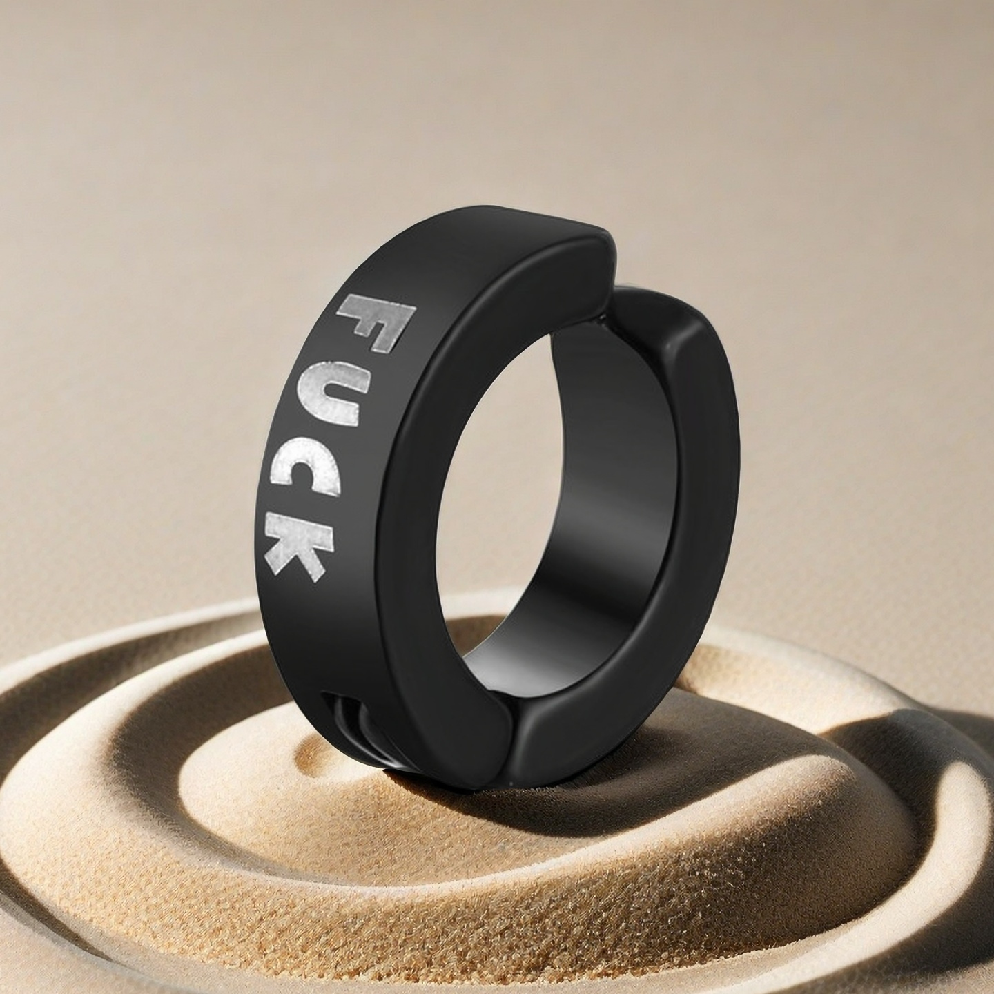 Black ring with engraved text on a beige surface