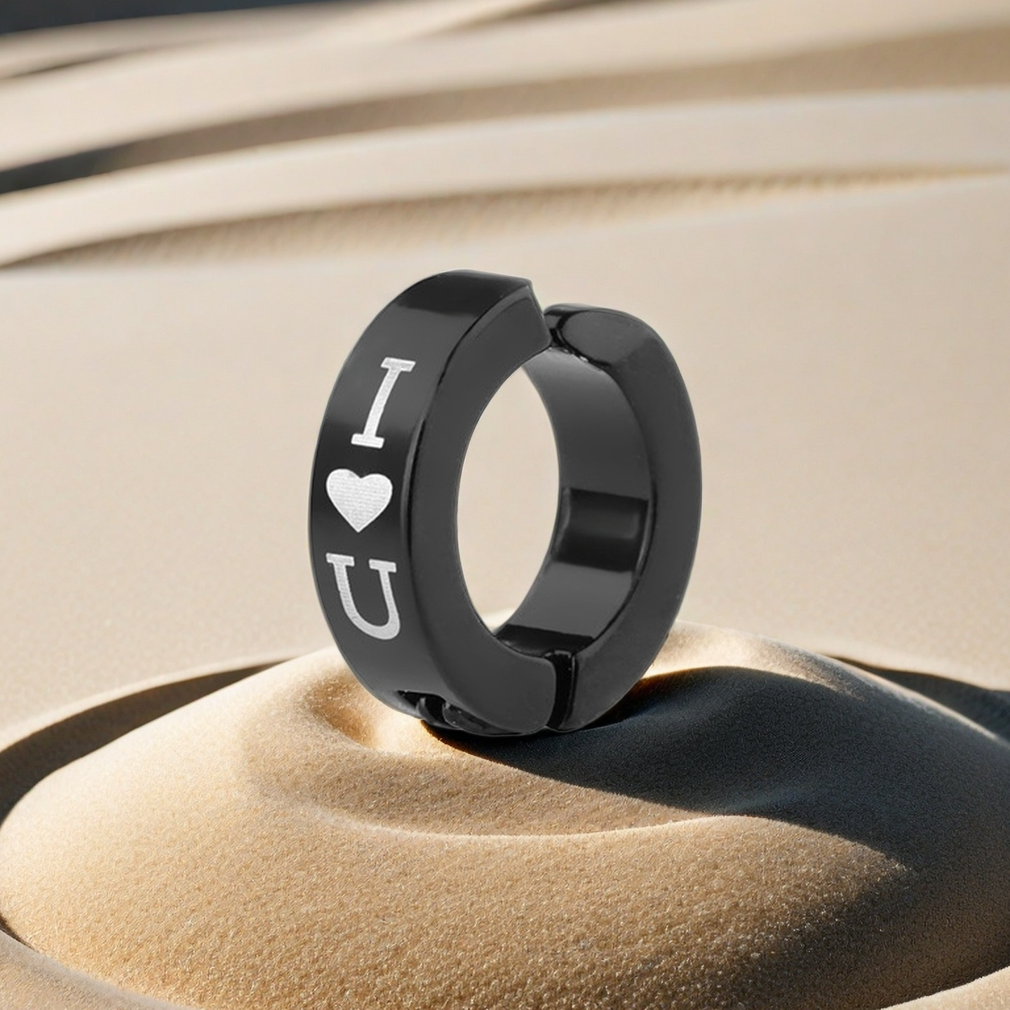 Black hoop earring with 'I ❤️ U' text on a sand background