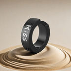 Black ring with 'KISS' engraving on a sand-like surface