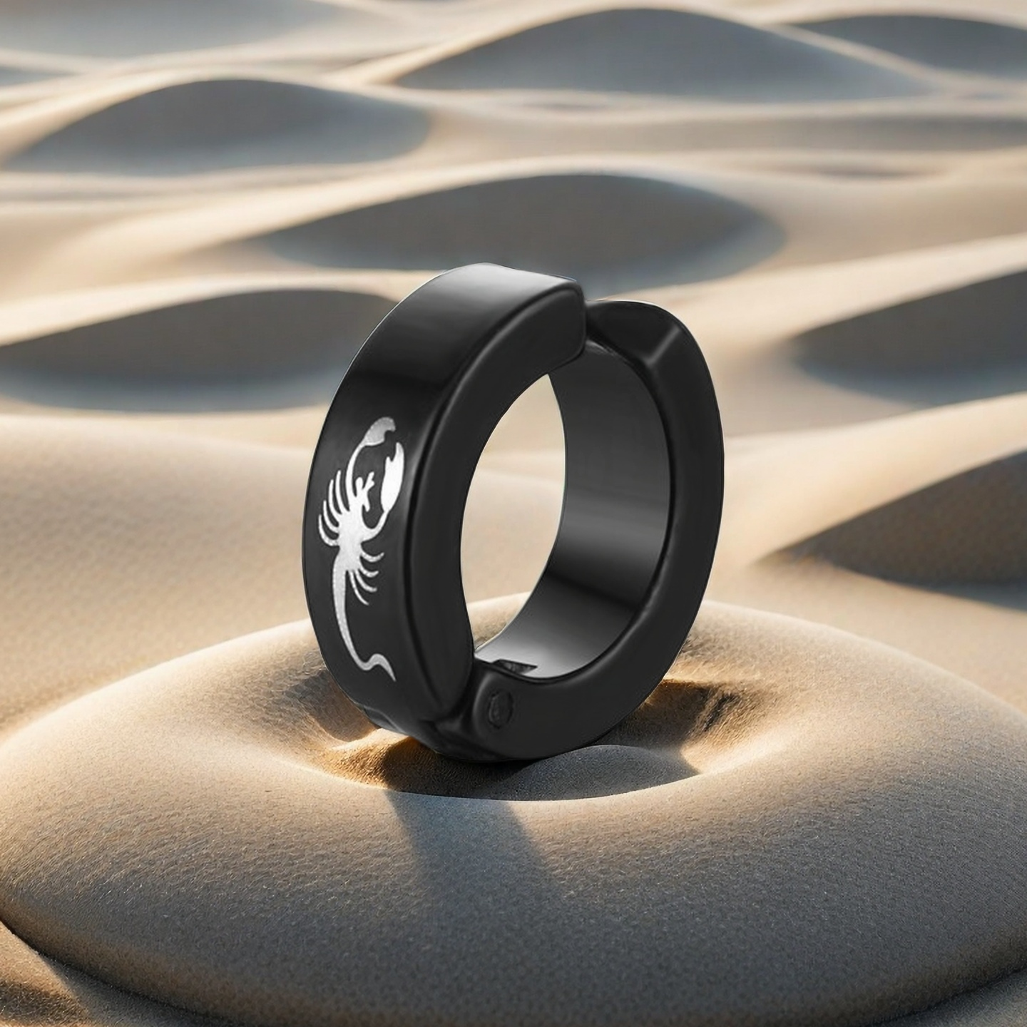 Black ring with a white scorpion design on sand