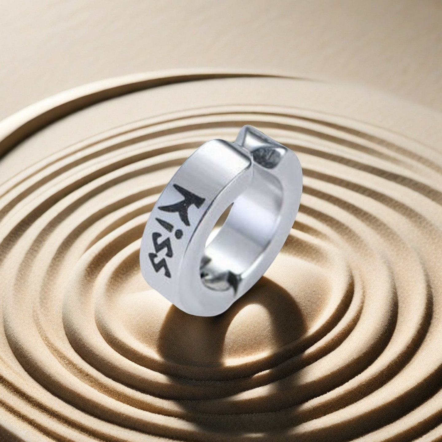 Silver ring with 'Kiss' engraving on a sand background