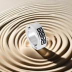 Silver ring with black geometric design on a sand background