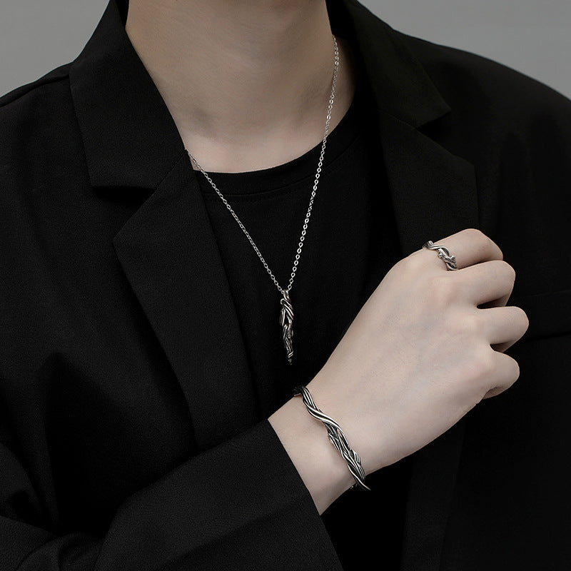 Person wearing silver jewelry including a necklace, bracelet, and ring on a black background