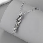 Silver wing-shaped pendant on a chain against a gray background